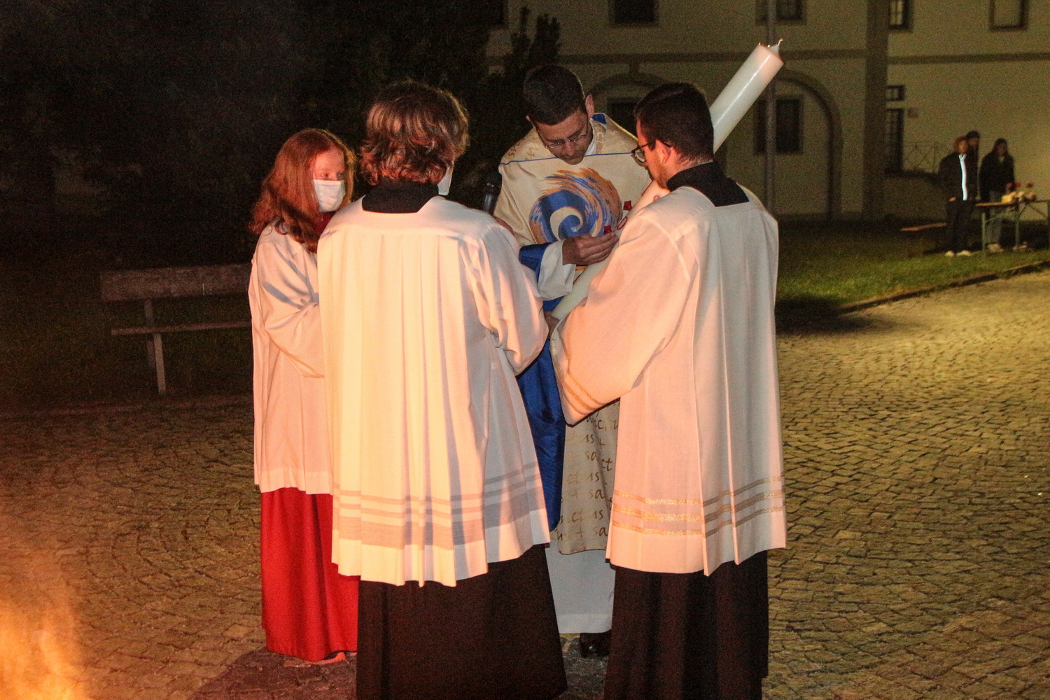 Pfarrer Oliver Rid und Praktikant Dominik Stefulic bereiten die Osterkerze im Beisein von Ministranten (G. Beck)